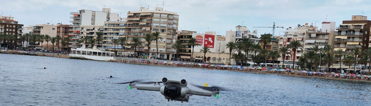 A DJI drone flying over the water in an urban area